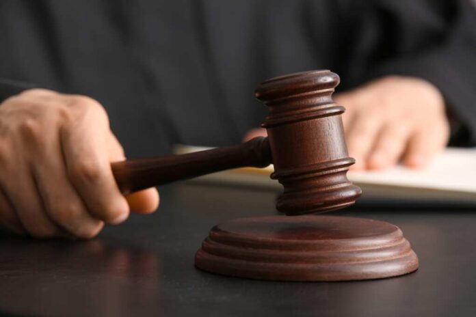 Male,Judge,With,Gavel,At,Table,In,Courtroom