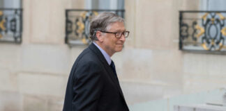 A man in a suit walking outdoors with a slight smile