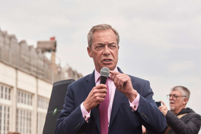 A man in a suit speaking into a microphone at an outdoor rally