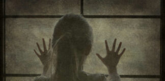 Silhouette of a child with hands pressed against a window, looking outside
