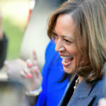 A woman smiling and engaging with a crowd at an outdoor event