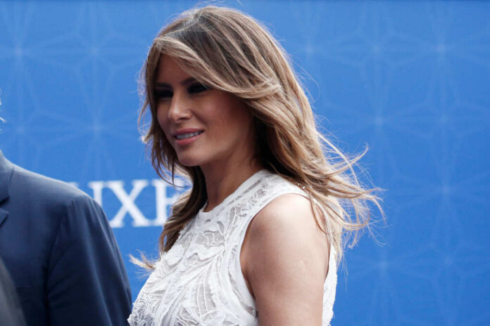 A woman with long hair wearing an elegant white dress, smiling at an outdoor event