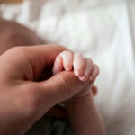 Rare Mutation Discovered—Doctors Admit Total Defeat A close-up of a babys hand being held by an adult hand