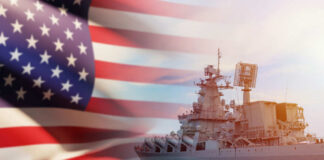 A naval ship with the American flag in the foreground