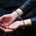 Child Abandonment to Fatal Crash: A Mother’s Descent Close-up of hands in handcuffs wearing a leather jacket