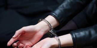 Close-up of hands in handcuffs wearing a leather jacket