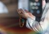 Person holding prayer beads with hands raised