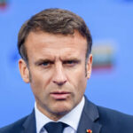 France’s President Sparks Free Speech Fury Close-up portrait of a serious-looking male political leader in formal attire against a blue background