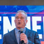 A man speaking into a microphone at a political event