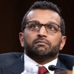 Close-up portrait of a man in formal attire with glasses, displaying a serious expression
