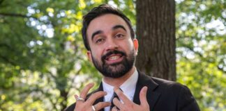 Man in business attire speaking outdoors with a natural background