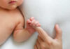 A close-up of a babys hand grasping an adult finger