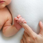 A close-up of a babys hand grasping an adult finger