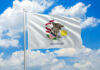 Illinois state flag waving against a blue sky with clouds