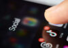 Digital ID Requirements: More Control or Safety? Close-up of a finger tapping a TikTok icon on a smartphone screen with social media labels
