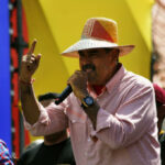 Maduro Gone: The Battle for Venezuela Begins A man in a straw hat passionately speaking into a microphone at a lively outdoor event