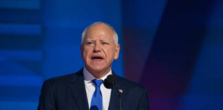 A man in a suit speaking at a podium with a microphone