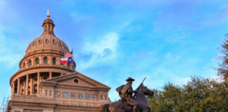 Statue of a rider in front of the Texas State Capitol building under a blue sky