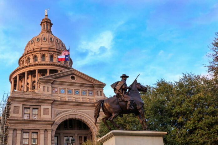 Statue of a rider in front of the Texas State Capitol building under a blue sky