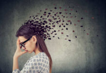 Mental Health Hijacked by Gender Ideology A woman with glasses holding her head, with fragments dispersing from her head