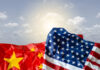 Crumpled flags of the United States and China against a cloudy sky
