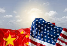 Crumpled flags of the United States and China against a cloudy sky