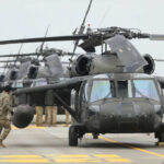 Military personnel preparing helicopters on an airbase