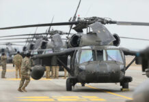 Military personnel preparing helicopters on an airbase