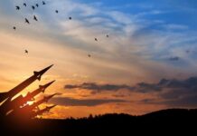 Silhouette of missiles against a colorful sunset with birds flying