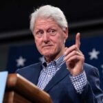 A public figure gesturing while speaking at a podium