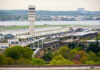 View of an airport terminal with a control tower and surrounding greenery