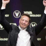 Person in business attire raising arms in celebration at a technology conference