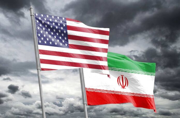Flags of the United States and Iran waving against a cloudy sky