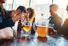 Group of friends enjoying drinks at a bar with a pitcher of beer on the table