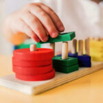 Childs hand stacking colorful wooden blocks