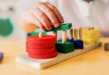 Childs hand stacking colorful wooden blocks