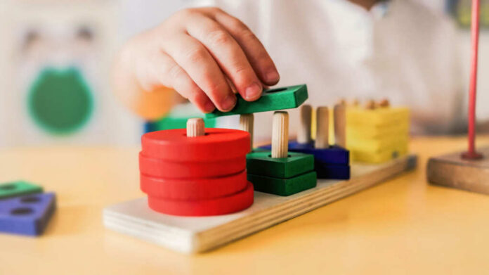 Childs hand stacking colorful wooden blocks