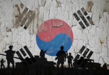 Silhouettes of soldiers in front of the South Korean flag on a cracked wall