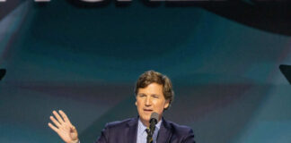 A man in a suit speaking at a podium with a microphone