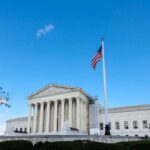 U.S. Supreme Court building with American flag and blue sky