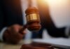 A judge's gavel being raised in a courtroom setting