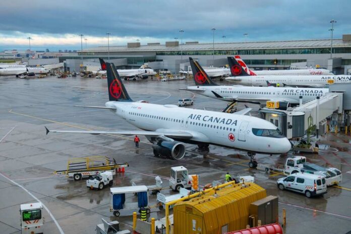 shutterstock_2557807297.jpg Air Canada planes parked at an airport terminal with ground crew working