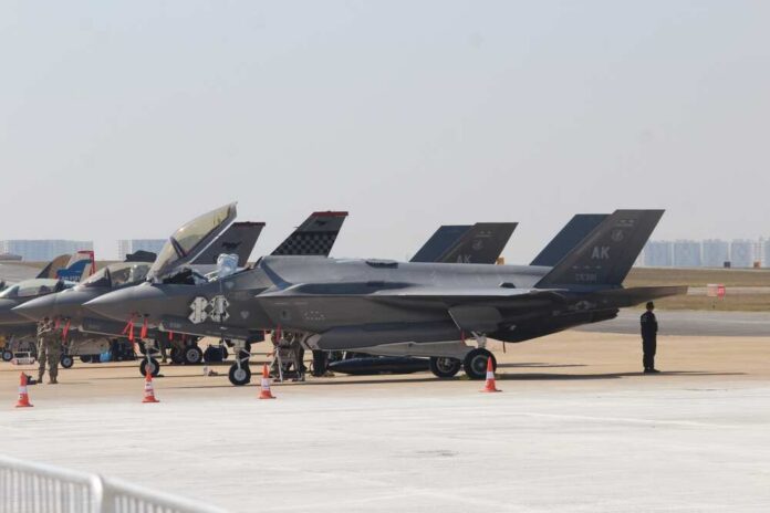 F-35 military jets parked on an airfield with crew members nearby