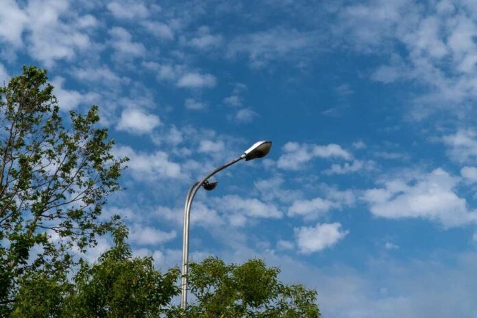 shutterstock_2642842385.jpg A streetlight against a backdrop of blue sky and scattered clouds