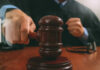 A judge striking a gavel on a wooden desk