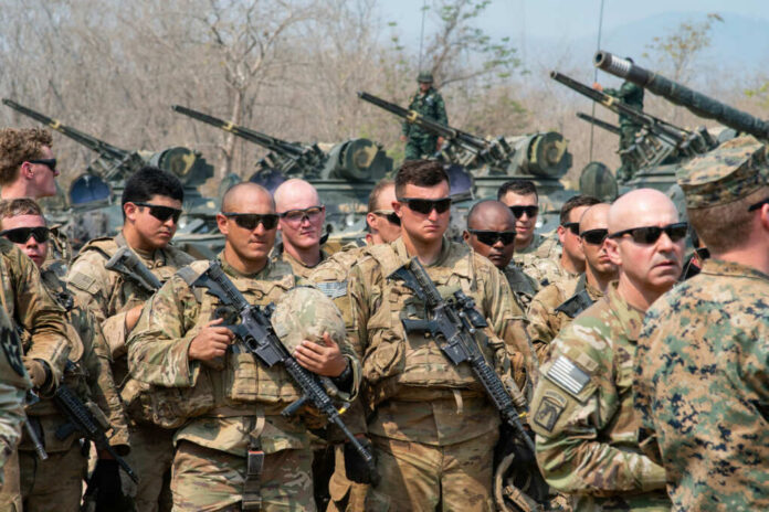 Group of military personnel in camouflage uniforms standing with weapons during a training exercise