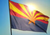 Arizona state flag waving against a bright sky