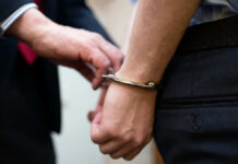 A close-up of a person being handcuffed by an officer