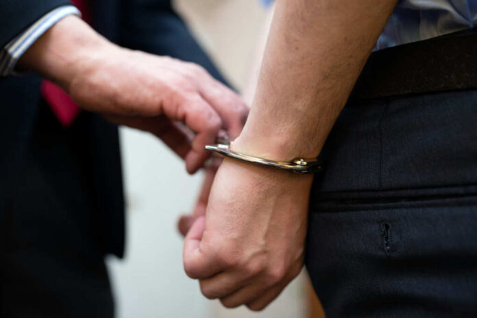 A close-up of a person being handcuffed by an officer