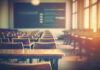 Empty classroom with wooden desks and chairs, illuminated by natural light